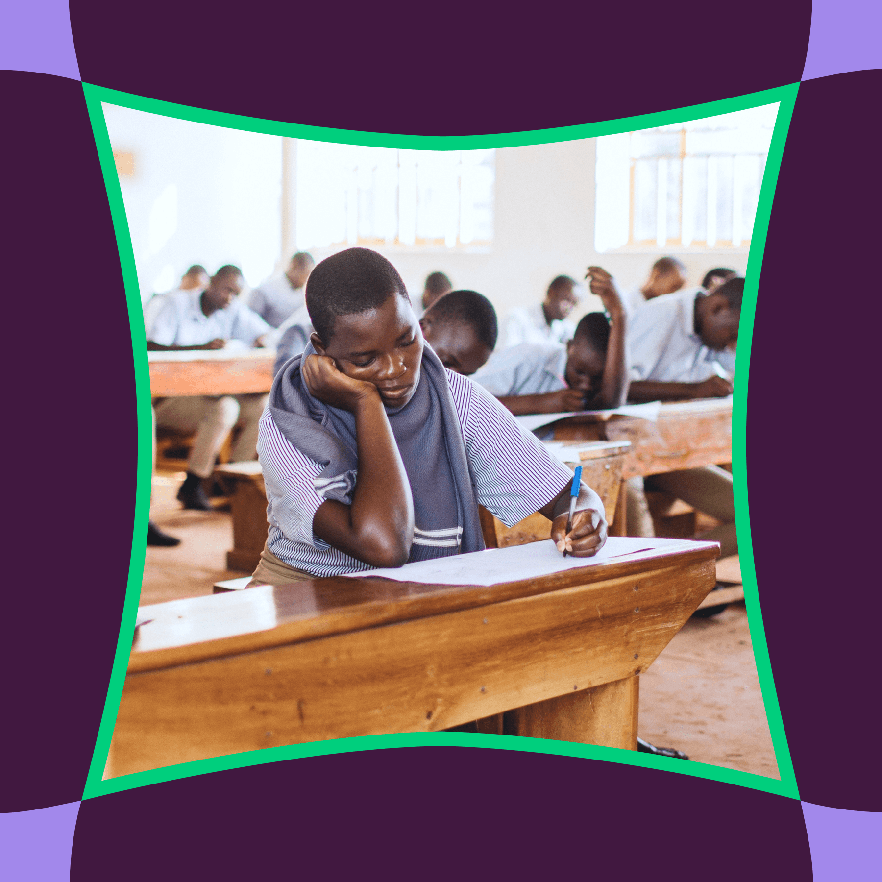 A student writing at a desk in a full classroom
